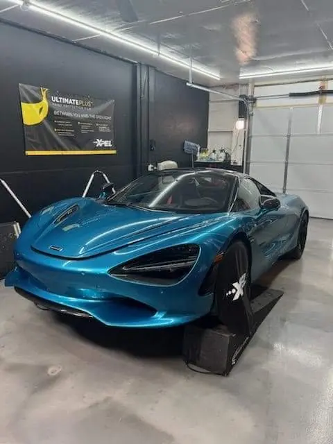 Blue McLaren supercar in the install bay with XPEL protective fender covers