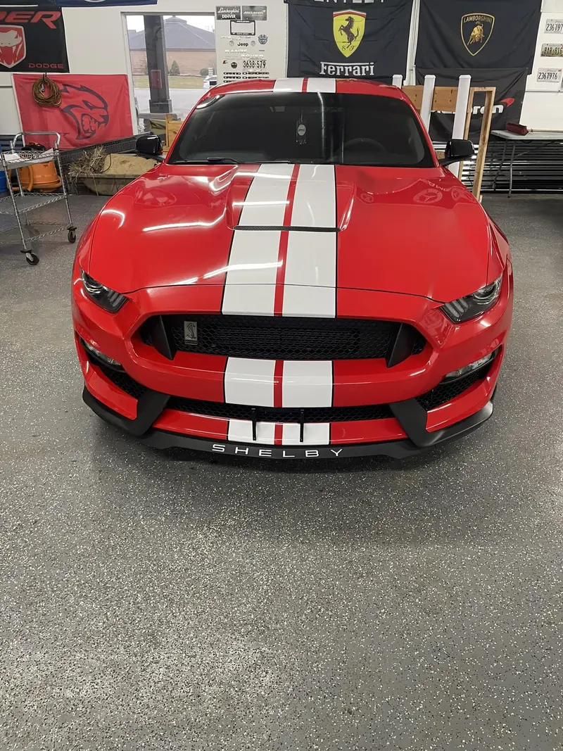 Red Shelby GT350 Mustang with white stripes, front view in the shop