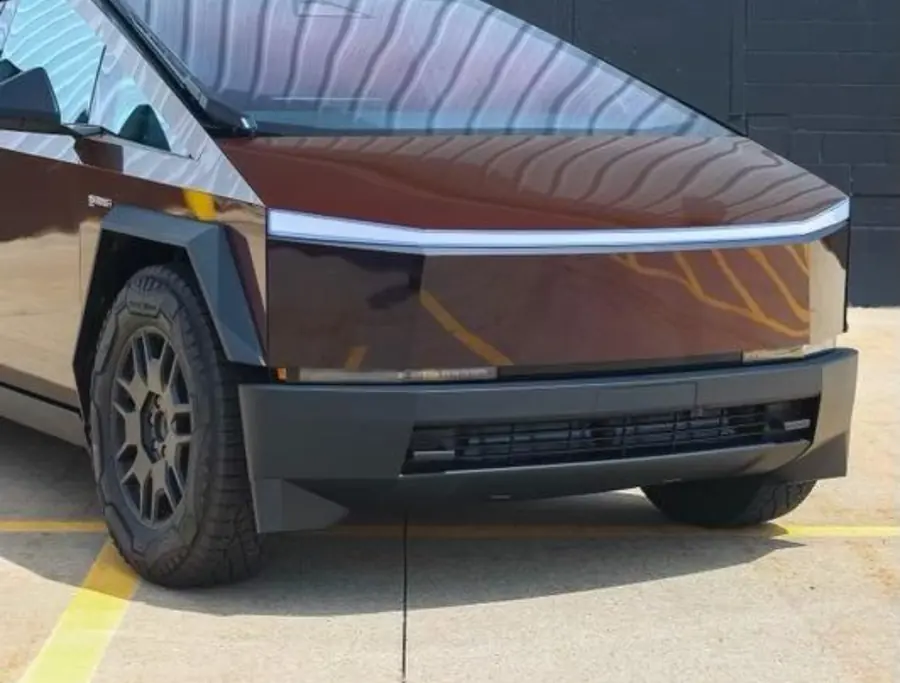 Tesla Cybertruck wrapped in a dark brown color film, parked outside the shop